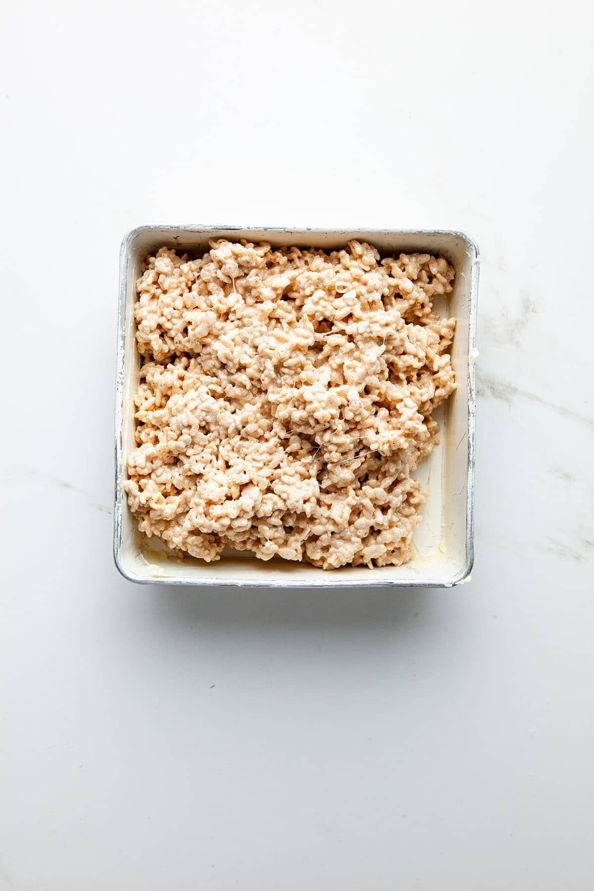 A pan of Rice Krispie treats before smoothing.