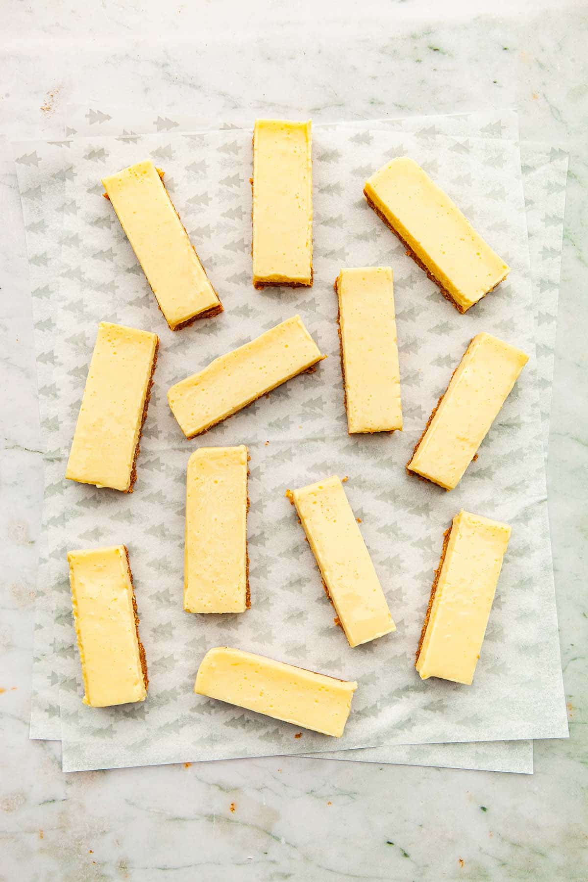 A batch of condensed milk lemon slices spread out on parchment paper on a marble background.