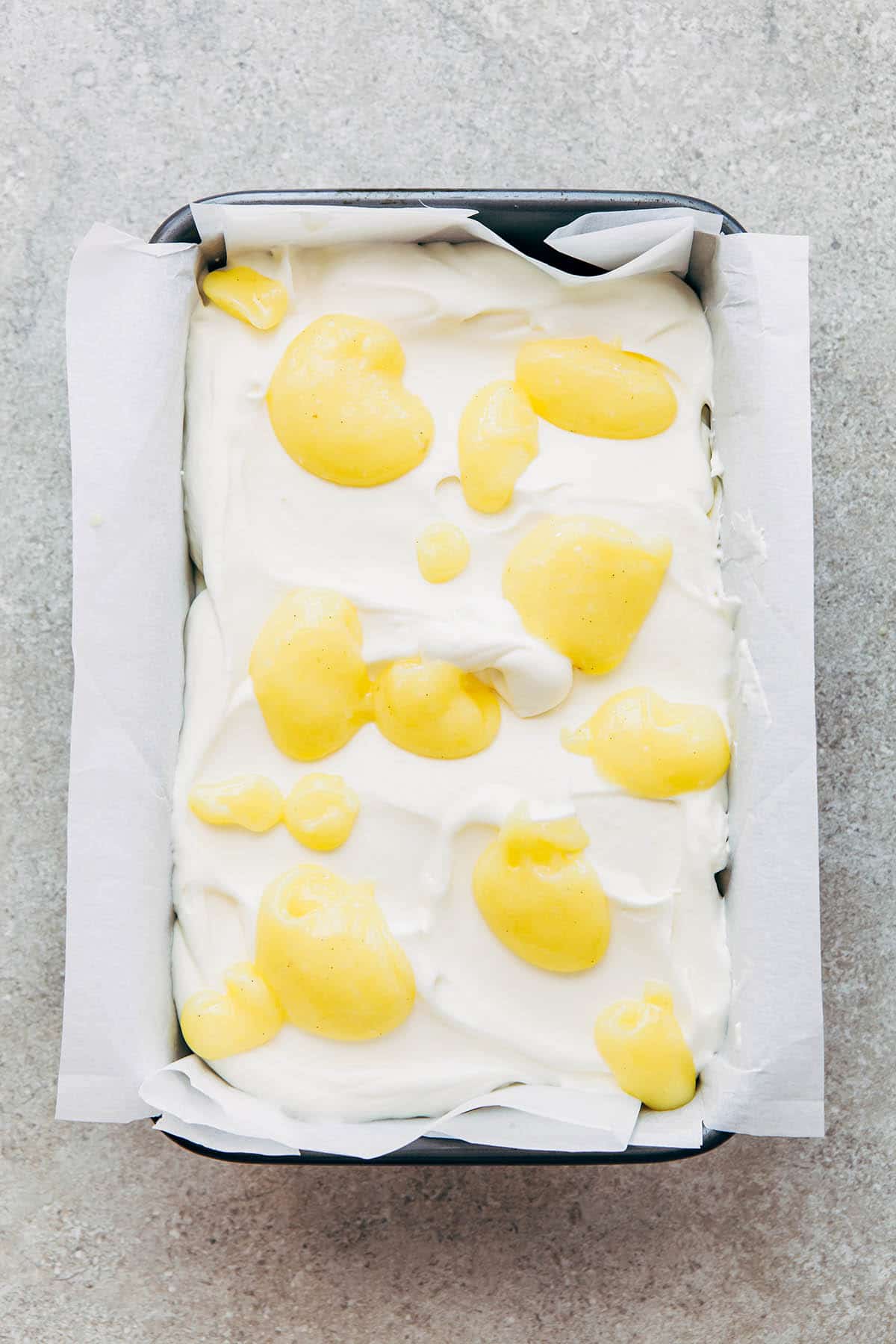 A loaf pan of whipped cream dolloped all over with lemon curd.