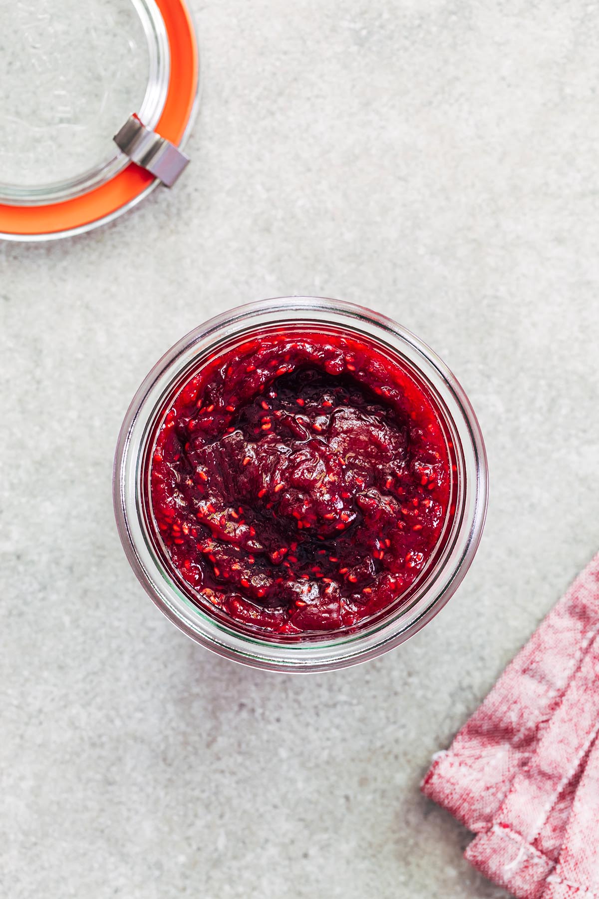 Close up overhead of a jar of raspberry rhubarb jam.