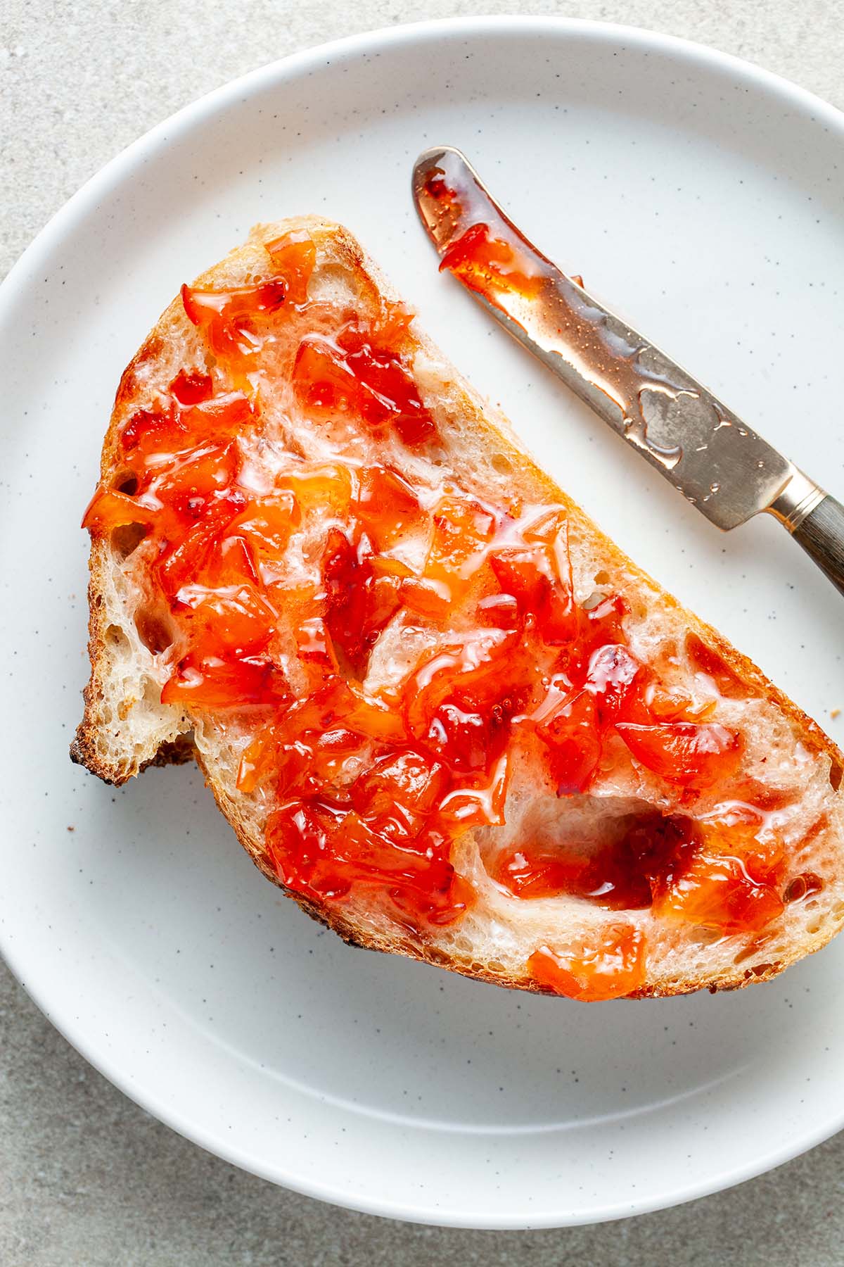 A slice of sourdough bread smeared with maple peach whisky jam.