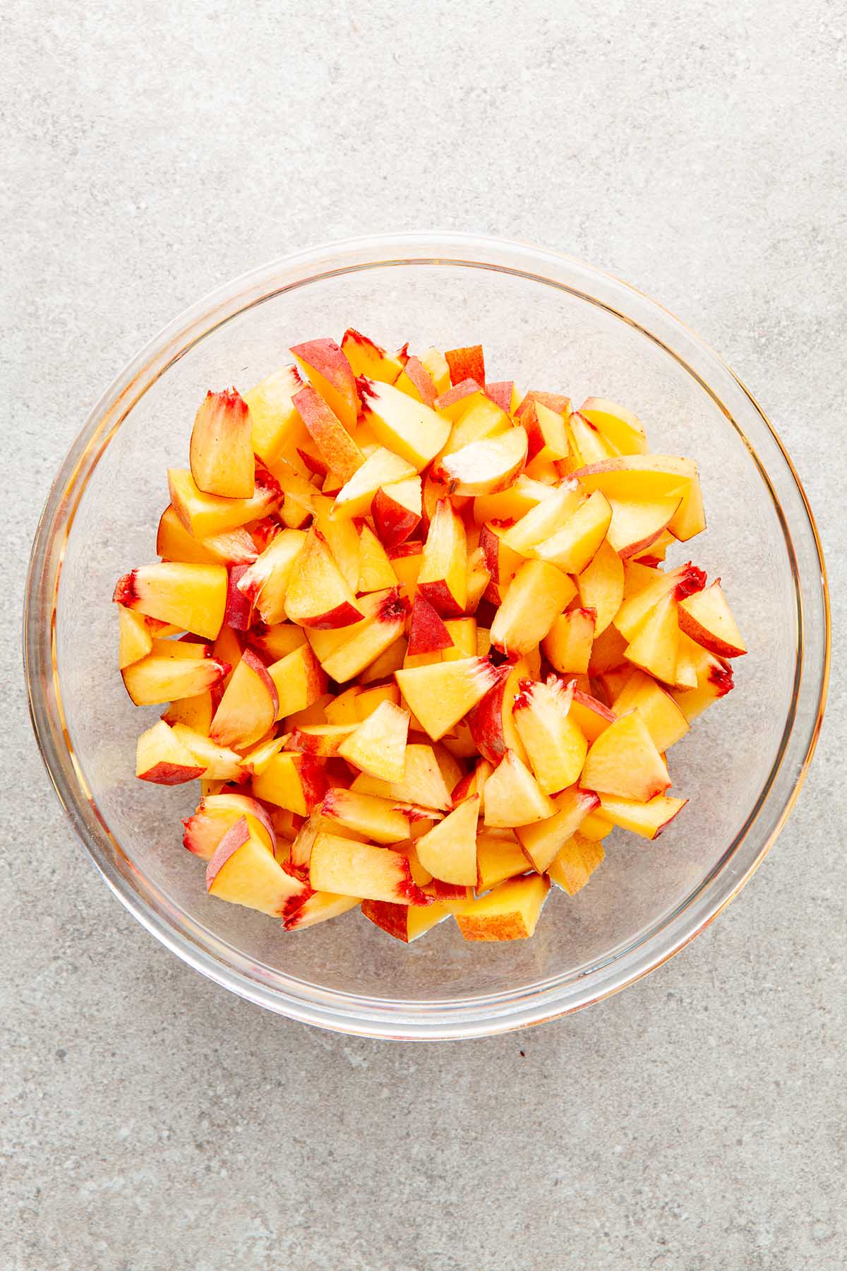A glass bowl of chopped peaches.