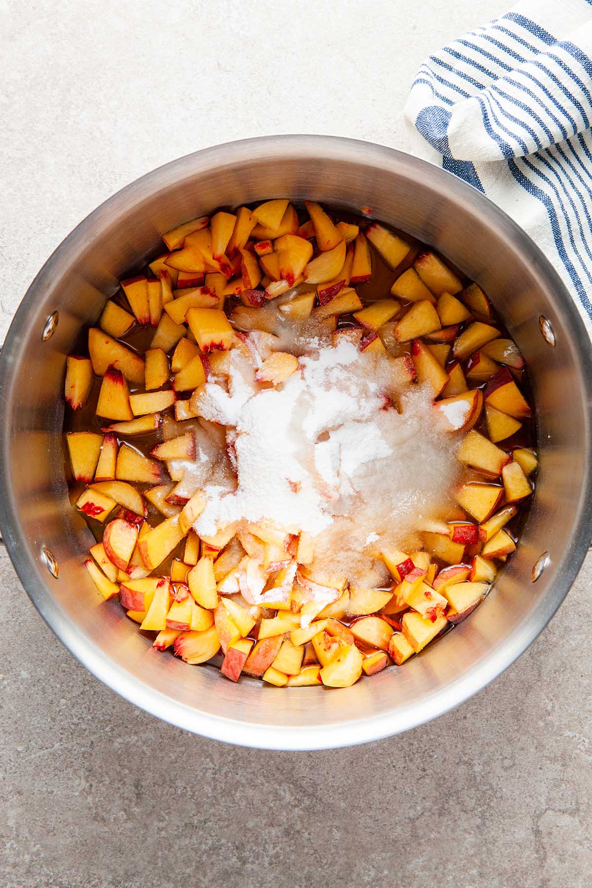 Chopped peaches, sugar, and maple syrup in a pot.