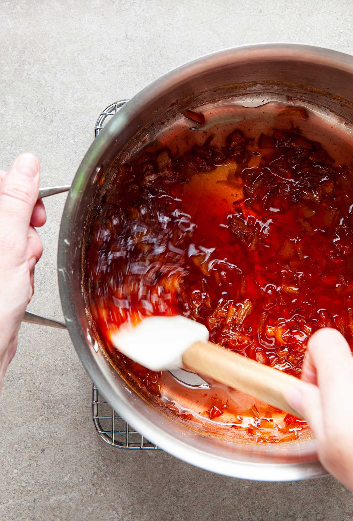 A hand stirring cooked small batch peach jam.