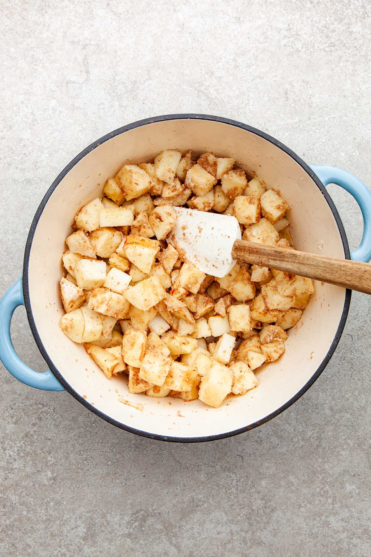 Apple chnk coated with flour and cinnamon in a pot.