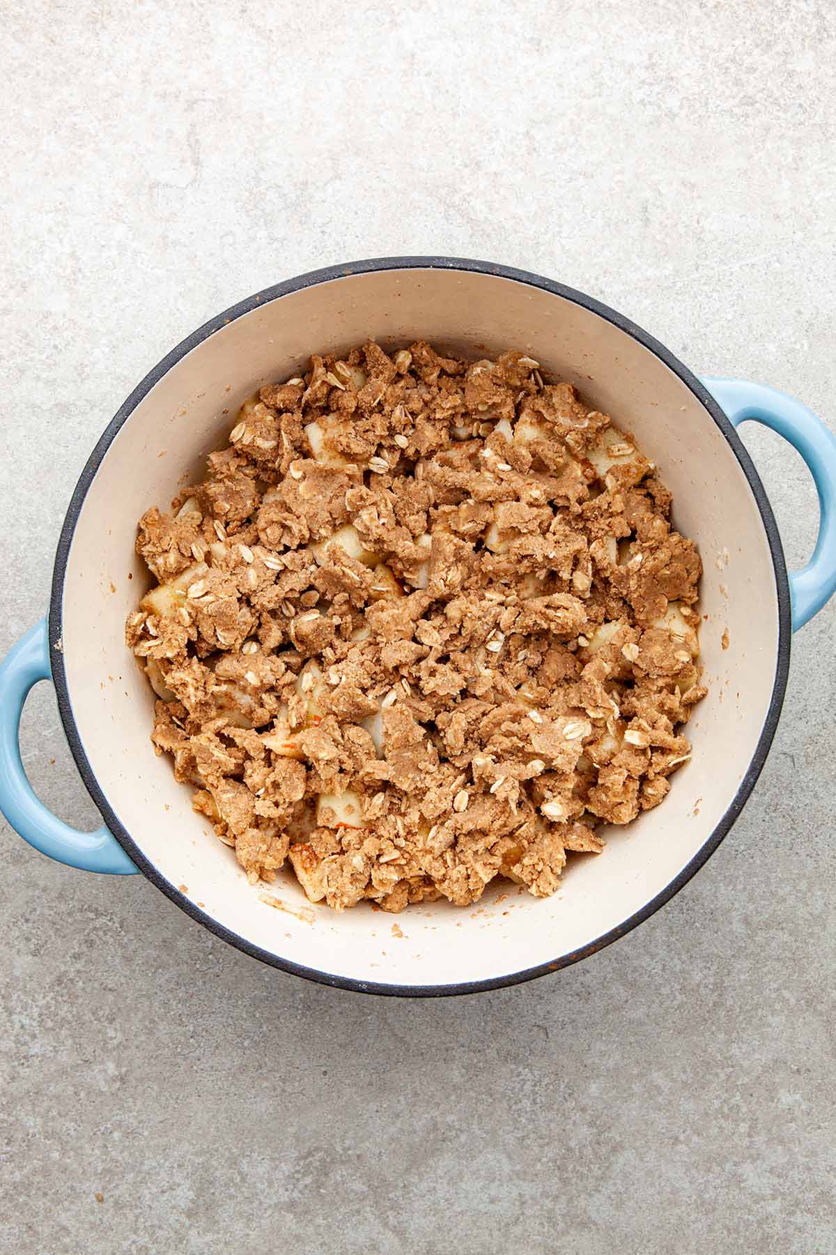 An unbaked fruit crisp in a blue enamel pot.