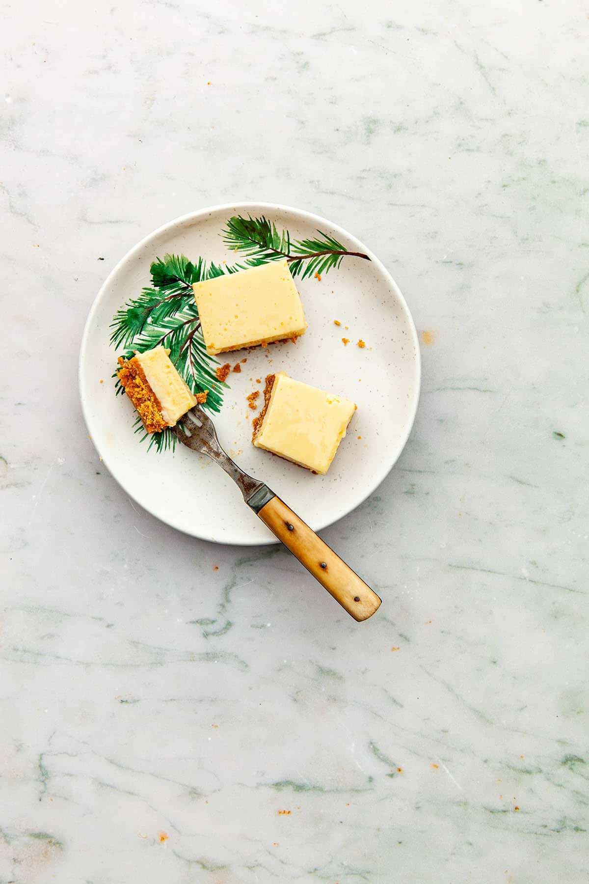 A condensed milk lemon slice on a plate with a bite cut out on a fork.