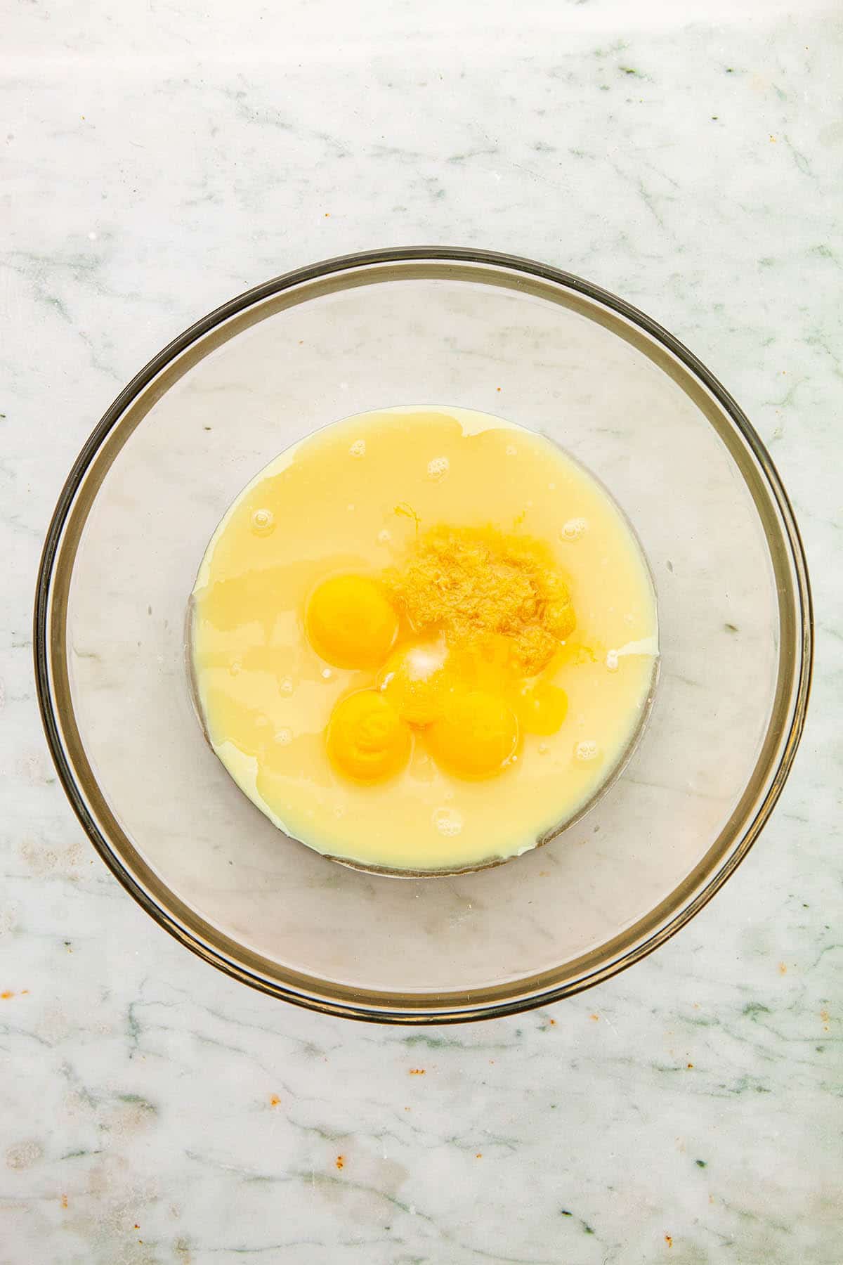 Un-whisked lemon filling ingredients in a large glass bowl.