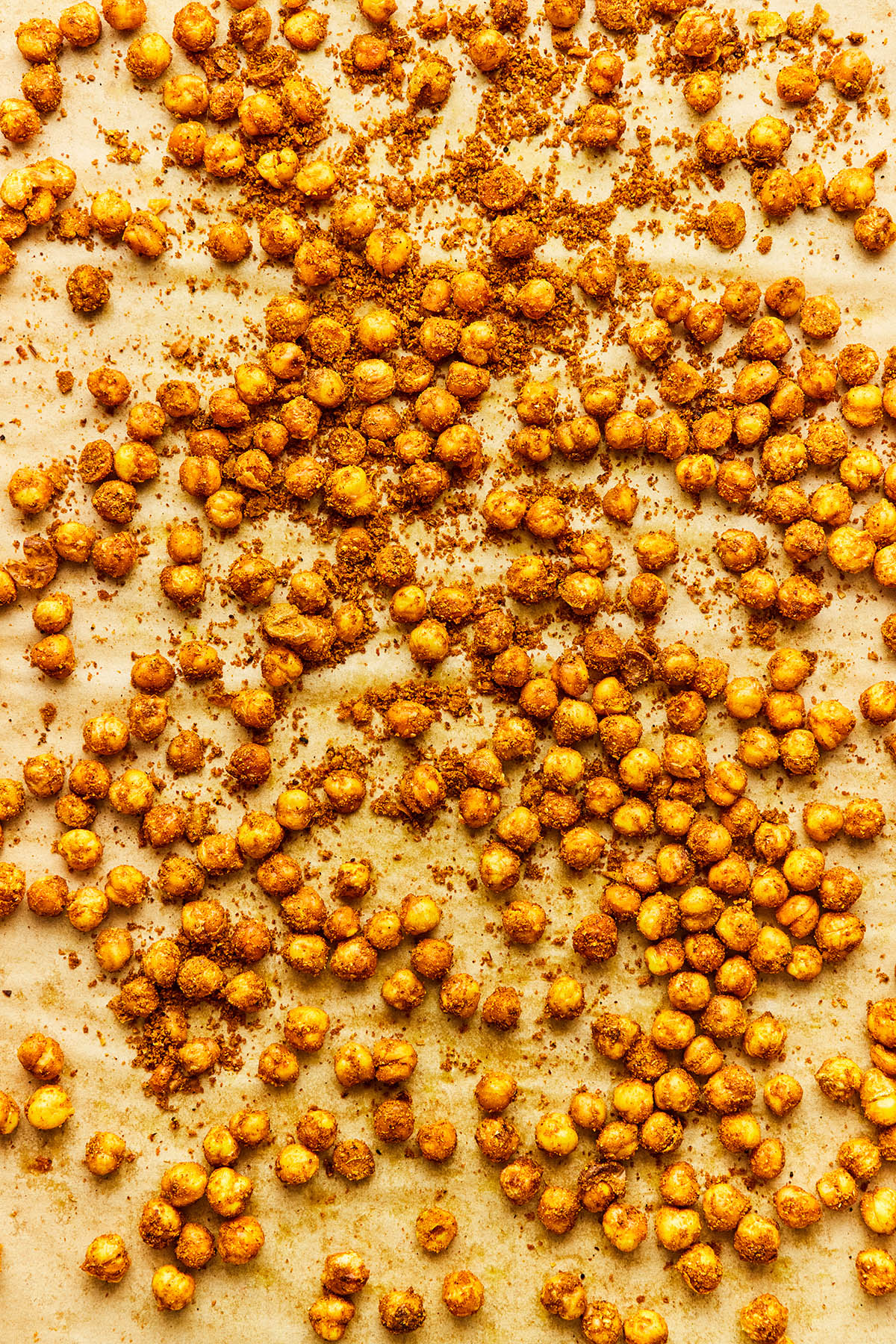 Cooked spiced chickpeas on a baking sheet lined with parchment paper.